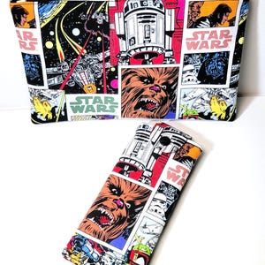 May include: A rectangular zippered pouch and a smaller, folded snap-closure case, both featuring a colorful Star Wars comic book print. The fabric displays illustrations of R2-D2, Chewbacca, Darth Vader, and various starships against a black background.