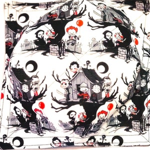 May include: Two white fabric bowl cozies with a black and white print of horror movie characters. The print features a house, a tree, and a crescent moon. The characters are holding balloons and other props.