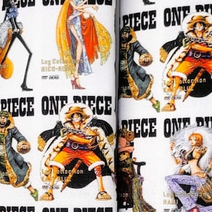 May include: White fabric items with a repeating pattern of colorful anime characters and the words "ONE PIECE". Includes a keychain and two fabric pieces, likely for a car seatbelt cover. The fabric has a black border.