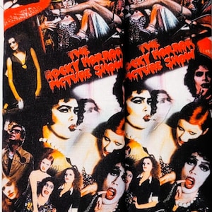 May include: Black lanyard and matching fabric item featuring a collage of images from The Rocky Horror Picture Show. The lanyard has a silver-colored metal clasp. The fabric item appears to be a glasses case or similar accessory.
