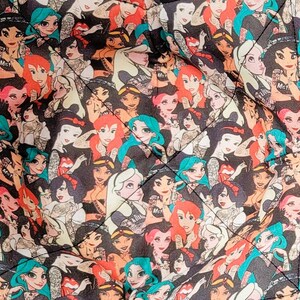 May include: Two square bowl cozies with a repeating pattern of cartoon women with various hair colors on a black background. The cozies are quilted and have a folded design.