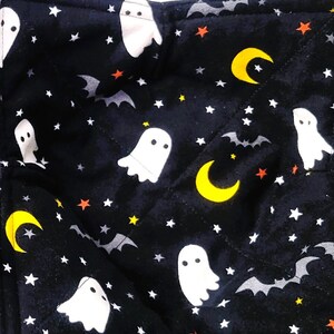May include: Two black quilted pot holders with a Halloween theme. The fabric features white ghosts, yellow crescent moons, orange stars, and gray bats on a black background.