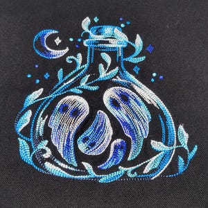 Könnte beinhalten: Stickerei mit einem blauen Glasflakon mit einer Mondsichel und Sternen, umgeben von wirbelnden Ranken und drei geisterhaften Figuren.