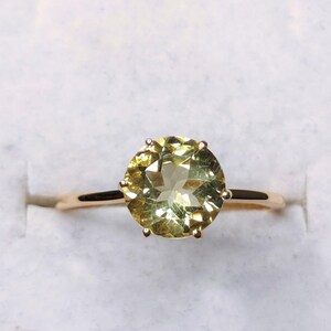 May include: A gold ring with a large, round, light green gemstone.