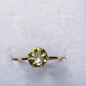 May include: A gold ring with a large, oval-shaped, light green gemstone set in a prong setting.