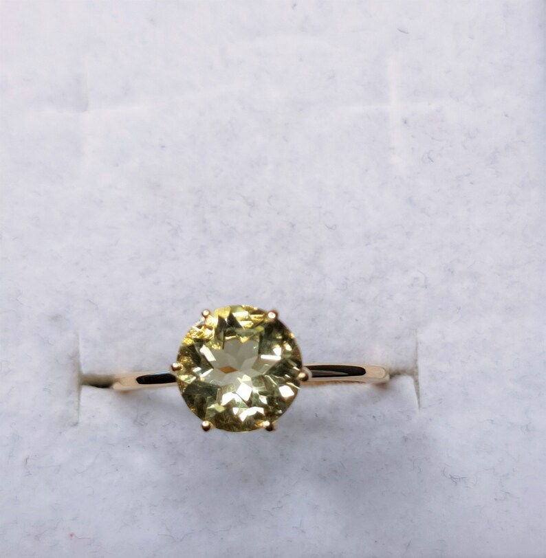May include: A gold ring with a large, oval-shaped, light green gemstone set in a prong setting.