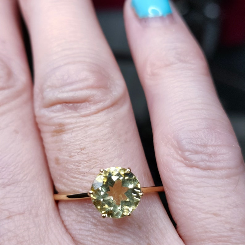 May include: A gold ring with a large, round, yellow gemstone. The gemstone has a star-shaped pattern inside.