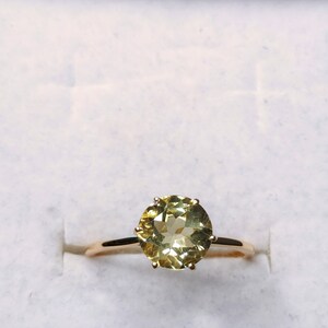 May include: A gold ring with a large, round, light green gemstone set in a prong setting.