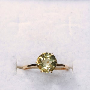May include: A gold ring with a round, faceted, light green gemstone.