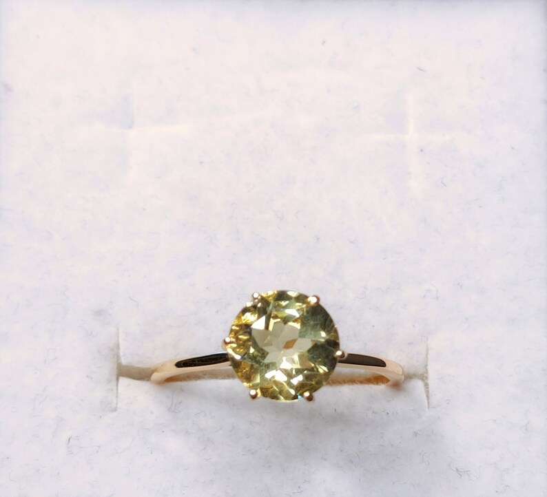 May include: A gold ring with a round, faceted, light green gemstone.