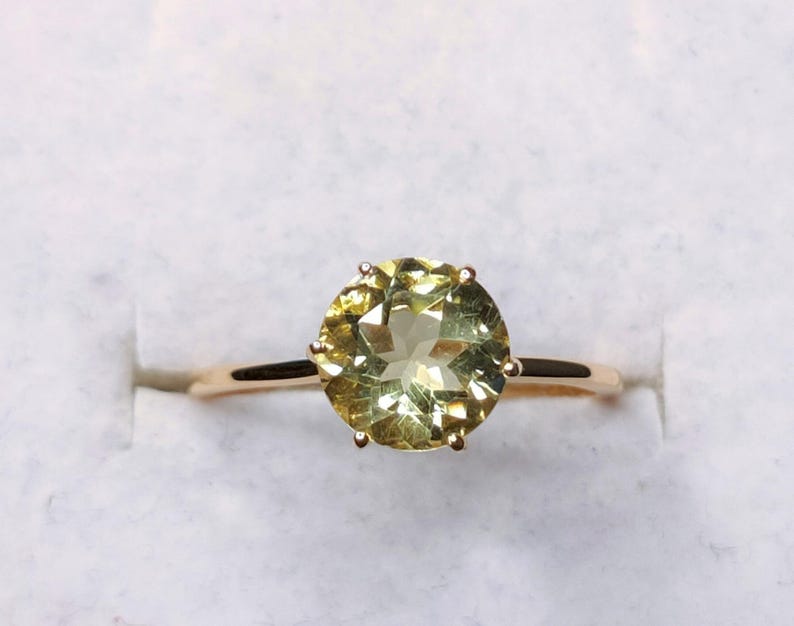 May include: A gold ring with a large, round, light green gemstone.