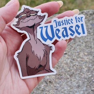 May include: A sticker featuring a cartoon weasel with a smug expression. The weasel is brown with a light brown chest and a white outline. The sticker has the text "Justice for Weasel" in blue.