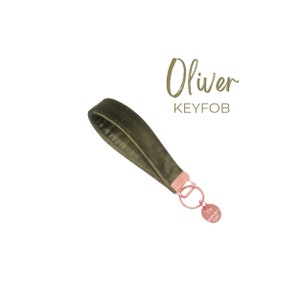 May include: A green velvet keychain with a rose gold key ring and a small rose gold charm that says "The Happy Place". The keychain is labeled "Oliver KEYFOB".