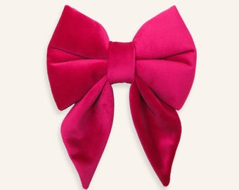 Peut inclure: Un grand nœud pour cheveux de couleur rose fuchsia vif, fabriqué dans un tissu en velours doux et pelucheux. L'accessoire présente deux larges boucles supérieures structurées et deux longues queues pointues tombant vers le bas.