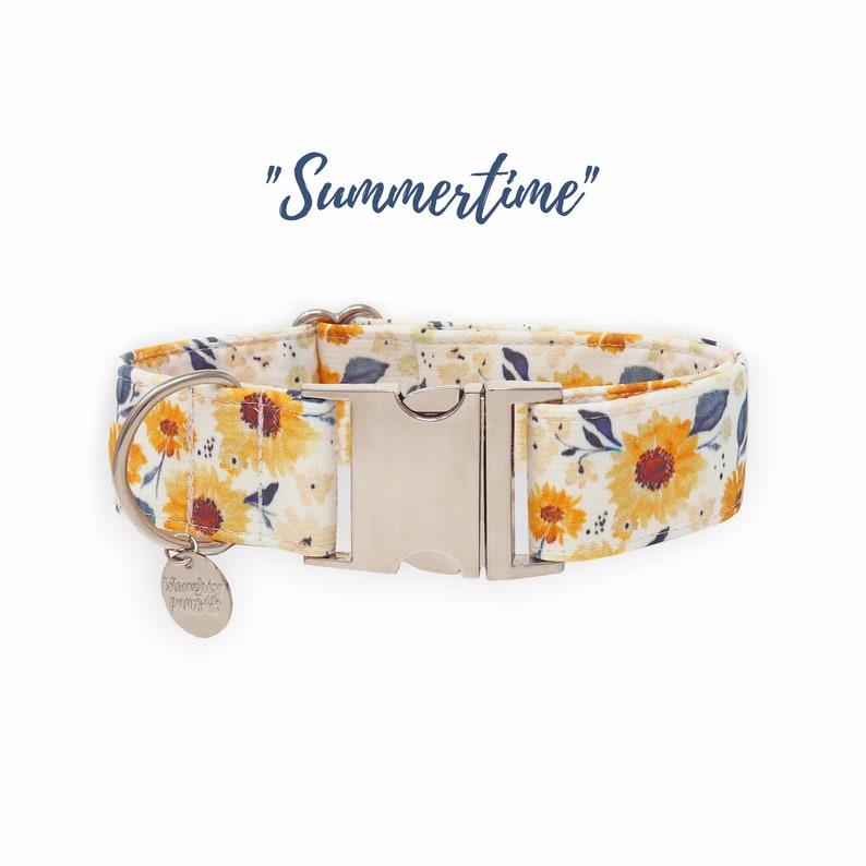 May include: A white dog collar with a sunflower print and a silver buckle. The collar has a small tag that says "Sleepy Puppy". The text "Summertime" is written in blue above the collar.