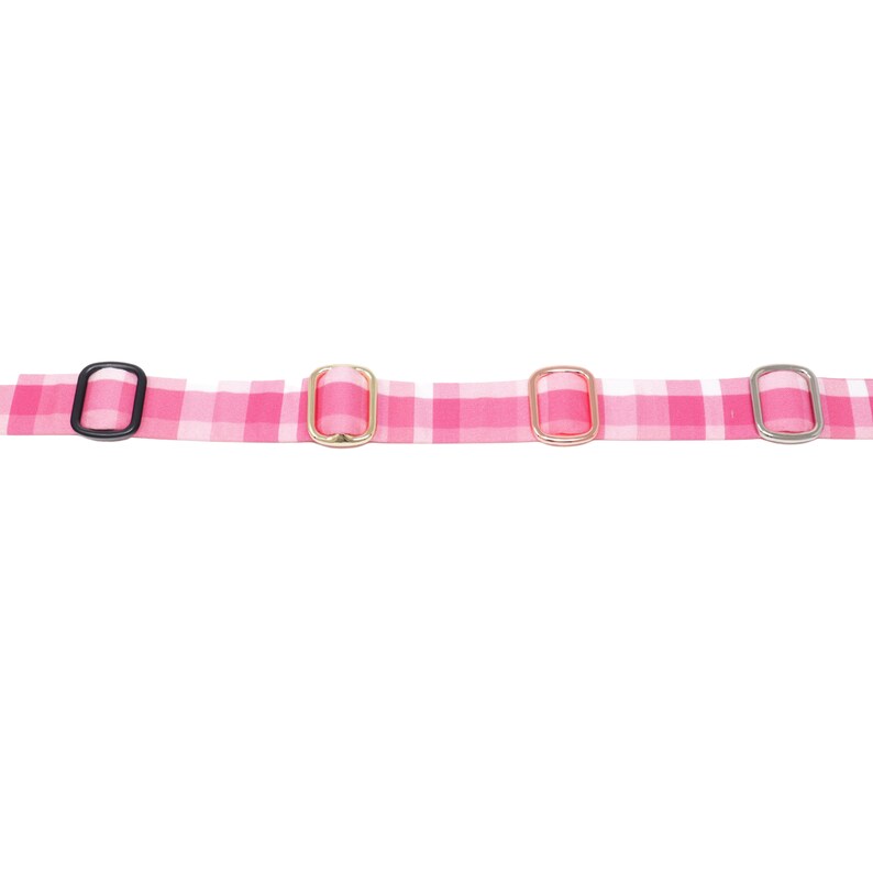 May include: Pink and white gingham ribbon with four different metal and plastic buckles. The buckles are black, gold, gold, and silver.