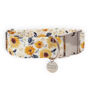 May include: White dog collar with a sunflower print and a silver buckle. The collar has a silver tag that says "Naughty Paws".