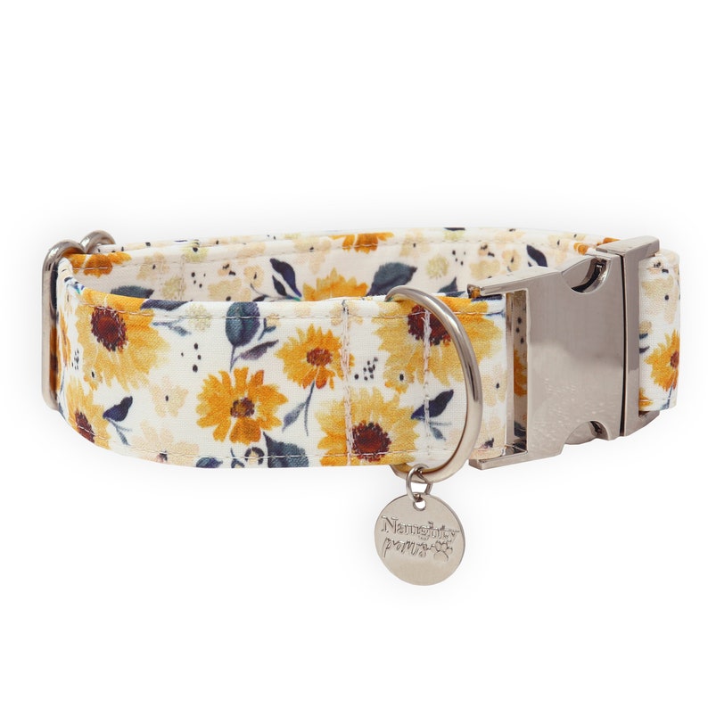 May include: White dog collar with a sunflower print and a silver buckle. The collar has a silver tag that says "Naughty Paws".
