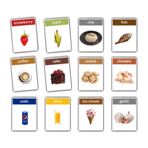 Pu&ograve; includere: Un set di 12 flashcard che mostrano vari alimenti, ognuno con la sua etichetta di parola corrispondente. Le flashcard sono disposte in una griglia 3x4, ogni carta ha uno sfondo bianco e un bordo grigio. Gli alimenti includono una fragola, mais, riso, pesce, caff&egrave;, torta, biscotti, pollo, bibita, succo, gelato e aglio.