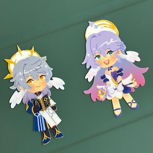 K&ouml;nnte beinhalten: Zwei Cartoon-Aufkleber mit Anime-Charakteren mit Engelsfl&uuml;geln und Heiligenscheinen. Eine Figur hat graues Haar und tr&auml;gt ein blau-wei&szlig;es Outfit und h&auml;lt ein Buch. Die andere hat lila Haare und ein wei&szlig;es und lila Kleid.