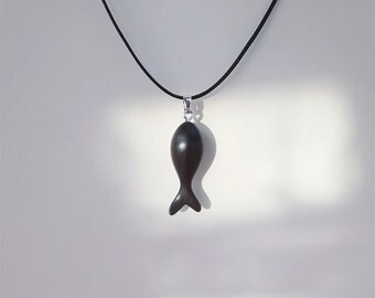 Puede incluir: Un collar con un colgante de pescado de madera negro en un cordón negro.