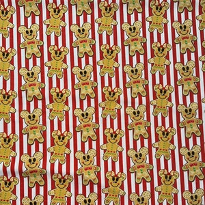 May include: A white fabric with a repeating pattern of gingerbread Mickey Mouse characters. The background is red and white stripes.