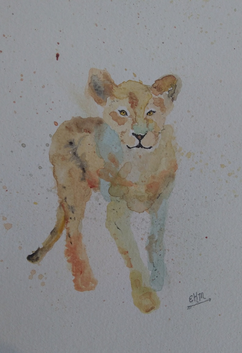 May include: Watercolour painting of a light brown lion cub with a light blue background. The cub is looking directly at the viewer. The artist's signature "EKM" is in the bottom right corner of the painting.