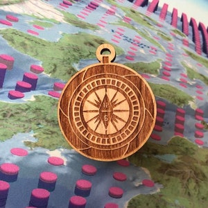 May include: A wooden compass pendant with a brown finish. The compass face features a traditional design with numbers 12, 6, and 3, and the letters N, E, S, and W.