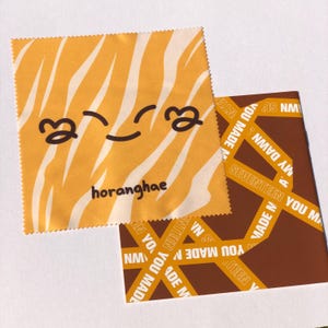 May include: A yellow and white striped microfiber cleaning cloth with a cartoon smiley face and the text "horanghae".