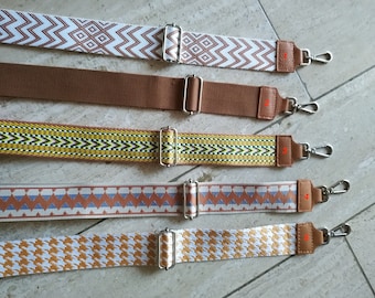 May include: Five different patterned fabric straps with silver buckles and metal clasps. The straps are brown, white, yellow, beige, and gold.