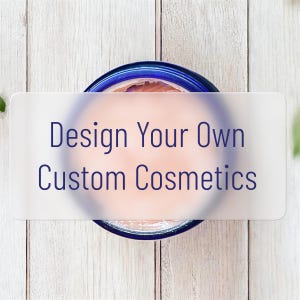May include: A jar of cosmetics with a blue rim and a light pink substance inside. The text "Design Your Own Custom Cosmetics" is overlaid on the jar in dark blue letters. The background is a light wood grain.