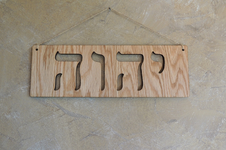 The sign is shown hanging from twine on a beige wall.