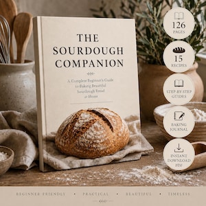 Może przedstawiać: Książka w twardej oprawie zatytułowana The Sourdough Companion, A Complete Beginner's Guide to Baking Beautiful Sourdough Bread at Home. Okładka przedstawia okrągły bochenek chleba na tkaninie. Okrągłe ikony wymieniają 126 stron, 15 przepisów, przewodniki krok po kroku, dziennik wypieków oraz natychmiastowe pobranie pliku PDF.