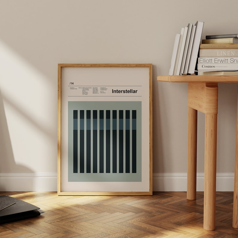 May include: A framed poster with a minimalist design featuring a light green background and a grid of dark blue and light blue vertical bars. The poster is titled "Interstellar" and has the number "1/14" in the top left corner.