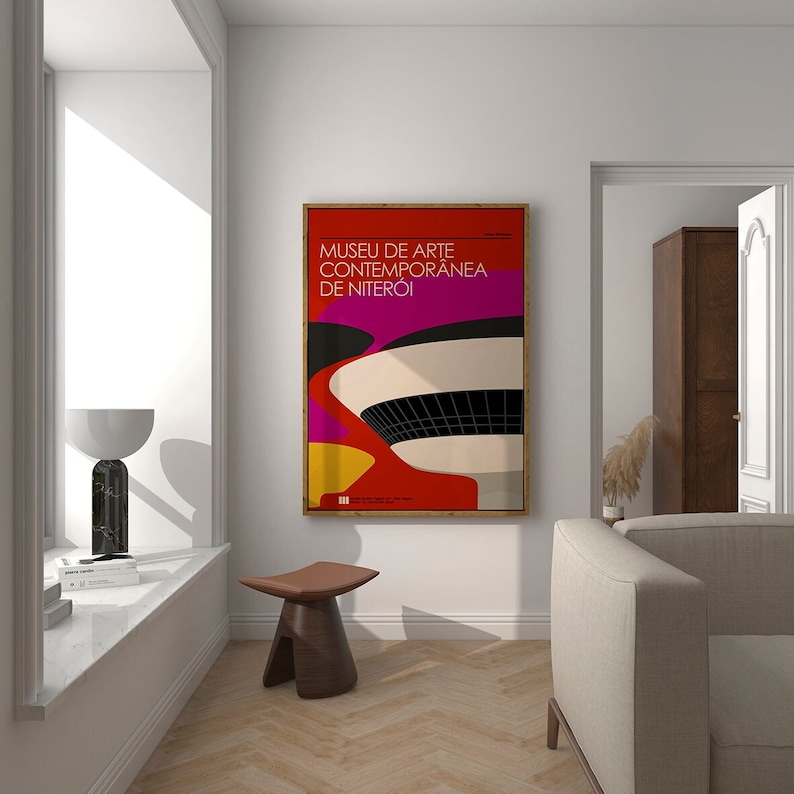 May include: A framed poster with a colorful abstract design of a building. The poster is titled "Museu de Arte Contemporanea de Niter&oacute;i" and is hanging on a white wall in a living room.