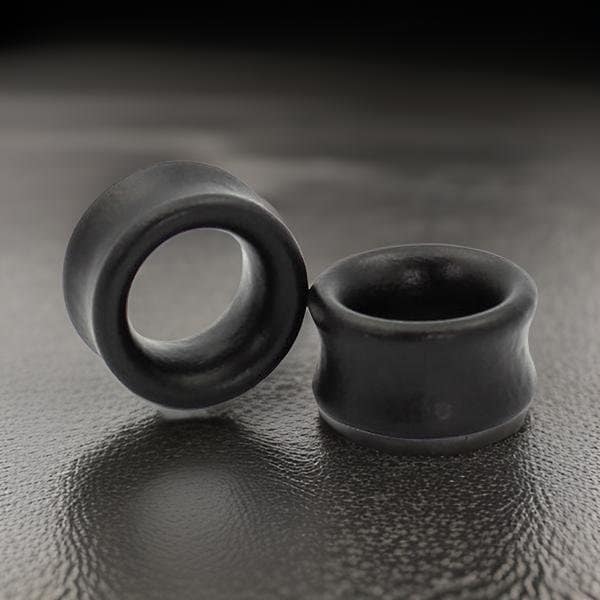 Könnte beinhalten: Zwei schwarze Ohrdehner, einer ist ein einfacher Ring und der andere ein ausgestellter Stopfen.