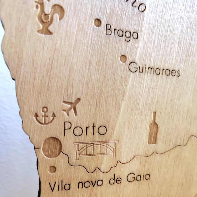May include: A detailed wooden map of a region, featuring engraved city names like Porto, Braga, and Guimaraes. The map includes etched icons such as a rooster, airplane, anchor, bridge, and wine bottle, all in a natural wood finish.