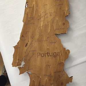 May include: Wooden map of Portugal, laser-cut with detailed geographical features and city names. The map is made of light brown wood, with the country's name prominently displayed. A decorative piece for home decor.