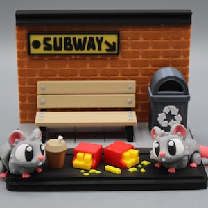 Może przedstawiać: Miniaturowa diorama przedstawiająca dwie myszy z kreskówek w scenie metra. Scena obejmuje ławkę, kosz na śmieci i znak z napisem "SUBWAY". Są też frytki i filiżanka kawy. Myszki są szare z różowymi ogonami i uszami.