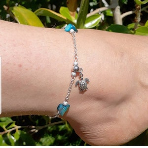 May include: A silver chain anklet with a small silver turtle charm and blue shell beads.