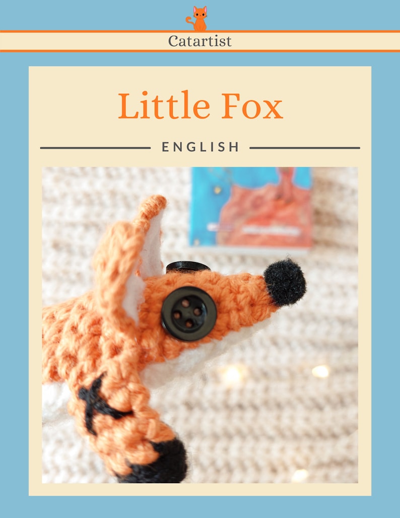 May include: A crocheted fox toy with black eyes and a black button nose. The fox is orange and white and is lying on a white knitted blanket.