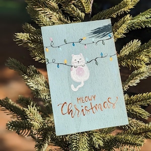 Carte postale de Noël, carte de voeux en bois peinte à la main avec chat blanc et lumières, Noël miaou, cadeau de vacances parfait pour les amis et la famille