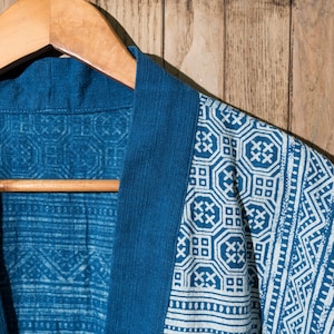 May include: A blue cotton robe with a white geometric pattern. The robe is hanging on a wooden hanger.