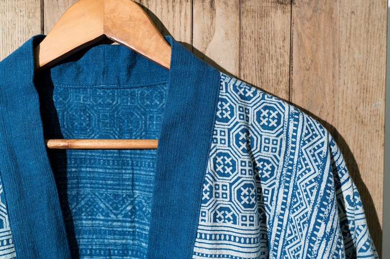 May include: A blue cotton robe with a white geometric pattern. The robe is hanging on a wooden hanger.
