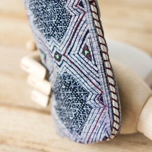 May include: A blue and white patterned fabric pouch with a red and white trim. The pouch is folded in half and has a geometric design.
