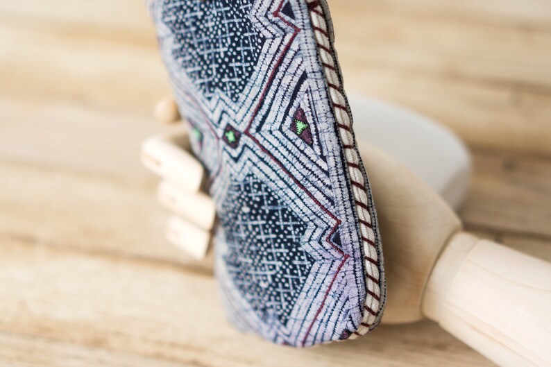 May include: A blue and white patterned fabric pouch with a red and white trim. The pouch is folded in half and has a geometric design.