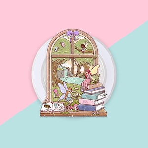 Op de afbeelding: Een gestanste sticker met een boogvormig raamkozijn met een paarse strik aan de bovenkant. Binnenin staan feeën afgebeeld in een bos met een waterval. Een stapel boeken met het label "Fairy Tale Books" staat op de vensterbank.