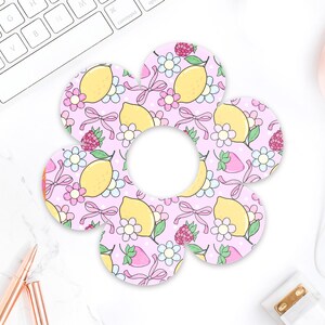 May include: A flower-shaped coaster set with a pink background, featuring a pattern of lemons, strawberries, flowers, and bows. The coasters are designed to protect surfaces from drink rings.