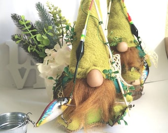 May include: Two green felt gnomes with long white beards are holding fishing rods with lures. One gnome has a lure attached to its rod and a small bucket is in the foreground.