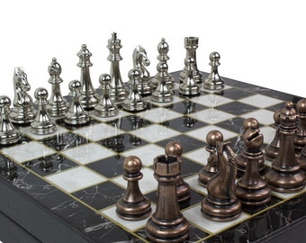May include: A chess set with silver and bronze pieces on a black and white chequered board. The board has a marble effect. The pieces are set up, ready to play a game of chess.